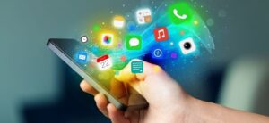 A hand holding a smartphone with colorful app icons streaming out, including messages, camera, calendar, and music, against a blurred background. The vibrant digital swirl symbolizes connectivity and technology, highlighting the church mobile app benefits for staying connected to your community.