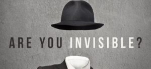 A black fedora hat and a suit with a white shirt appear against a textured gray background, with the text "ARE YOU INVISIBLE?" capturing the curiosity of new people in search of connection.