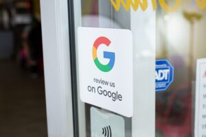A Google Reviews sticker on a glass door invites patrons to "review us on Google." The sticker, adorned with the iconic Google logo and flanked by security badges, stands prominently at the entrance of this small-town church, enhancing its SEO presence online.
