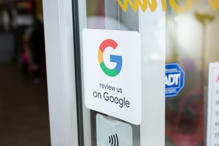 A Google Reviews sticker on a glass door invites patrons to "review us on Google." The sticker, adorned with the iconic Google logo and flanked by security badges, stands prominently at the entrance of this small-town church, enhancing its SEO presence online.
