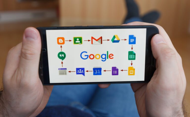 A person holds a smartphone showcasing the Google logo, surrounded by icons of Google Tools like Drive, Gmail, Calendar, and Docs. Connected by arrows, these apps help communicate and organize seamlessly.