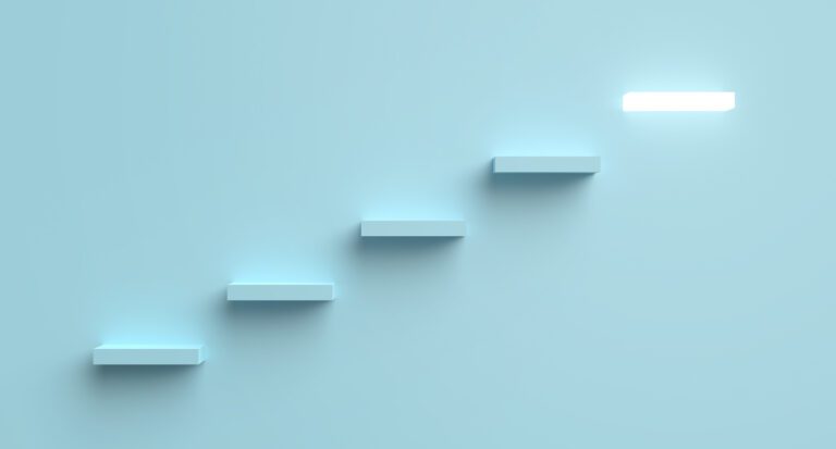 A minimalist image illustrating five white, rectangular steps ascending against a light blue background. The ascent signifies the next steps toward a bright, glowing rectangle at the top right, symbolizing a final destination or goal.
