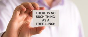 A person in a white shirt is holding a card with the text "THERE IS NO SUCH THING AS A FREE LUNCH," a stark reminder amidst conversations about free services and paid services.