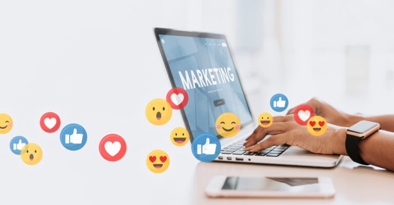 A laptop displaying the word "Marketing" is being used by a person. Surrounding it, various social media reaction icons like thumbs up and hearts float, symbolizing online engagement—a perfect illustration for church promotion strategies or increasing enthusiasm for a Christmas service.