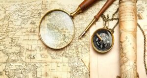A vintage map with a magnifying glass, an ink pen, a compass, and a rolled-up scroll invoke the spirit of spiritual explorers. These objects create an antique exploration theme with sepia tones.